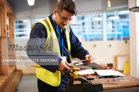 Male student using carpenters rule in shop class workshop