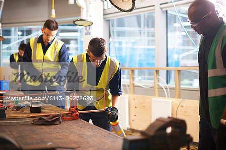 Male instructor watching student welding in workshop