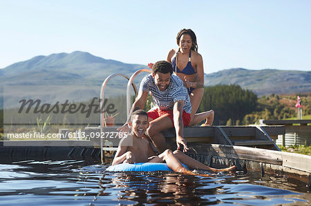Happy family swimming in sunny, summer swimming pool