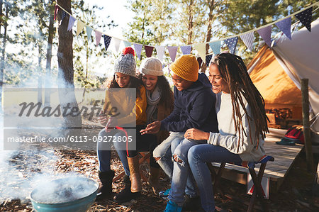 Happy lesbian couple and kids relaxing at campsite in woods