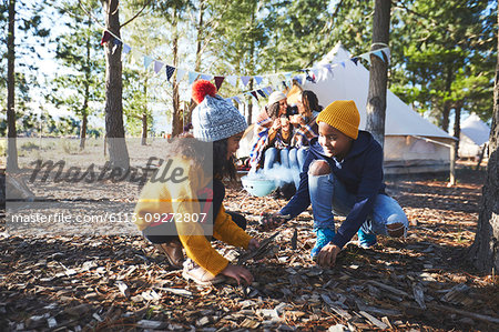 Brother and sister gathering kindling at campsite in woods