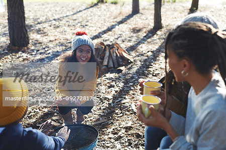 Happy family relaxing around camping grill at sunny campsite