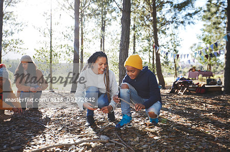 Mother and son gathering firewood kindling at campsite in sunny woods