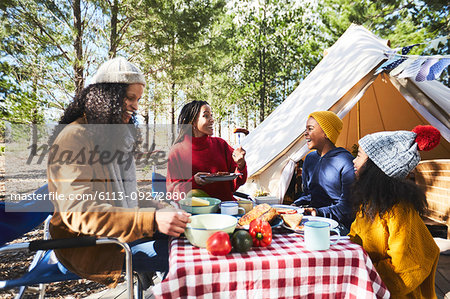 Lesbian couple and kids eating at sunny campsite
