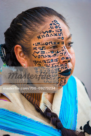 Portrait of a female indigenous tribal dancer with symbols painted on her face at a St Michael Archangel Festival parade in San Miguel de Allende, Mexico