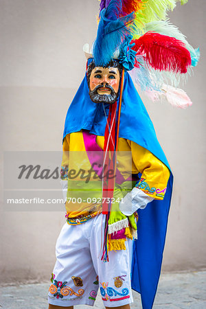 Man posing in colorful costume and mask at a St Michael Archangel Festival parade in San Miguel de Allende, Mexico
