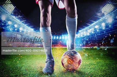 Soccer player with soccerball on fire at the illuminated stadium during the match