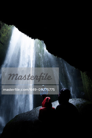 Tourists below overhanging rock in front of waterfall, Selfoss, Arnessysla, Iceland