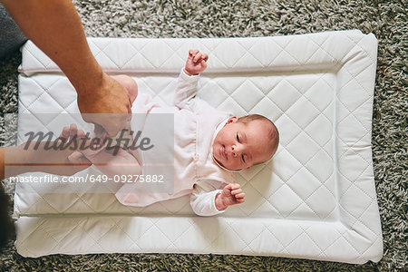 Father changing baby's diaper at home