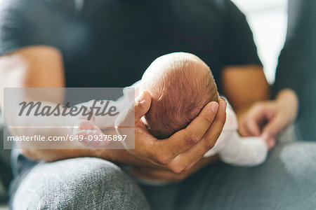 Father supporting head of baby on lap