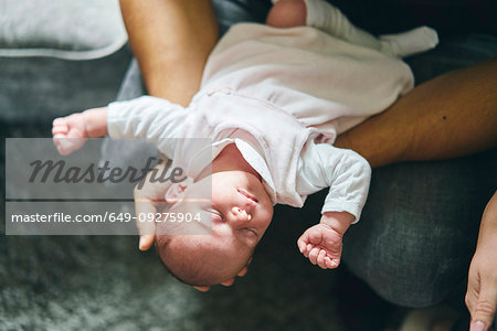 Father supporting head of baby on lap