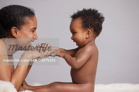 Mother playing with baby sitting on furry blanket