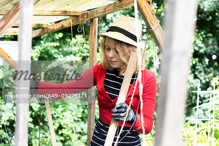 Mid adult woman constructing wooden shelter in her garden