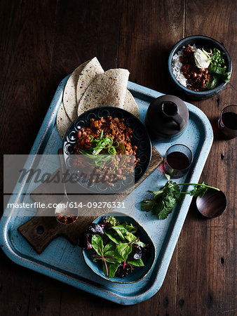 Rustic low key still life with tray of chilli con carne, salad and coffee, overhead view