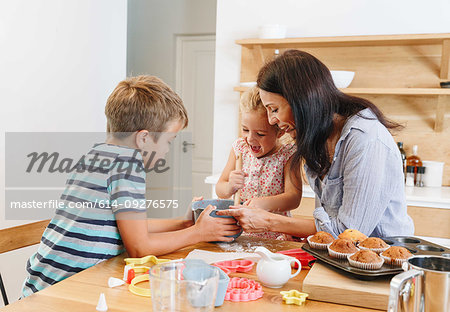 Mother and children baking cupcakes in kitchen