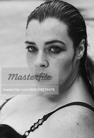 Sultry mid adult woman with wet hair leaning against outdoor swimming poolside, black and white head and shoulder portrait, Cape Town, South Africa