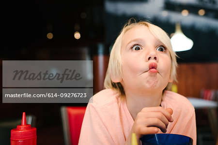 Cute blond haired boy in airport cafe pulling a face, head and shoulders