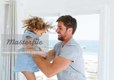 Father playing and swinging daughter in beach house