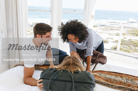 Couple playing with daughter on bed in beach house