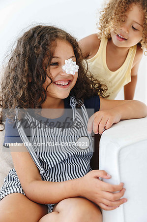 Sisters smiling over paper flower on nose