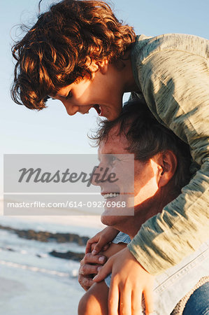 Father giving son piggyback ride on beach