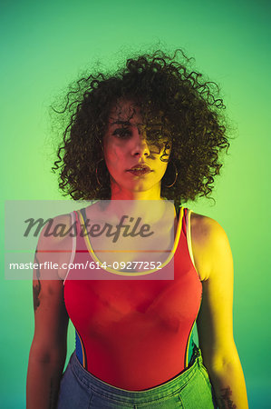 Young woman in red tank top posing against green background