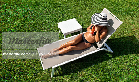 Woman relaxing with mocktail in deckchair on lawn