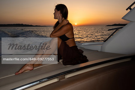 Woman in bikini relaxing on yacht at sunset