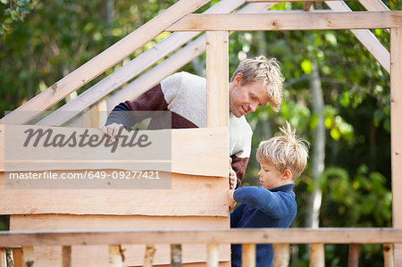 Father and son building treehouse together in garden