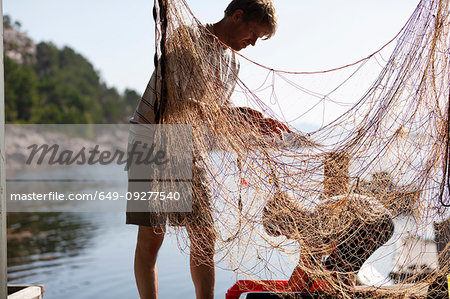 Fisherman and boy disentangling fishing net