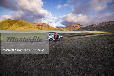 Woman traveller enjoying scenic view beside vehicle, Landmannalaugar, Highlands, Iceland