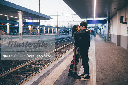 Young couple kissing on train station platform, Milan, Italy