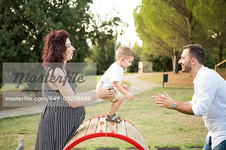 Parents playing with son on circular swing in park