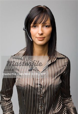 Young woman with telephone headset, isolated on grey background in studio