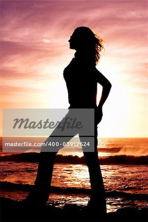 Silhouette of a woman at sunset on the beach.