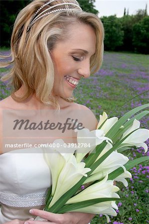 A bride standing in flowery field holding her bouquet