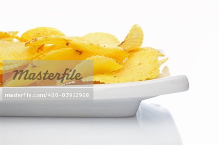 Potato chips on a plate reflected on white background