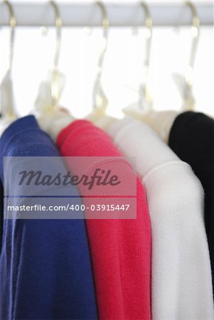 Colorful women's sweaters on a rack on padded hangers