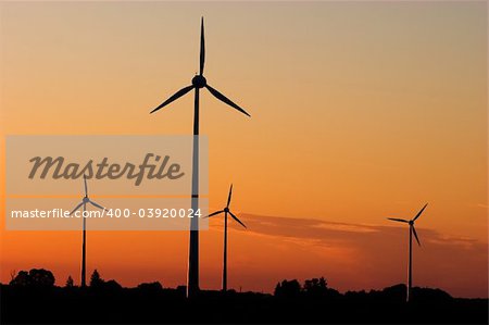 Four windturbines against dramatic sunset producing environment friendly energy