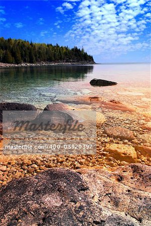 Beautiful view on a rocky shore with clear water and golden reflections at sunset. Georgian Bay, Canada.