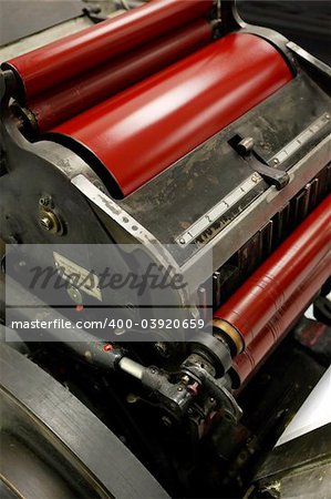 Image of an old windmill printing press / die cutter / numbering machine, with bright red ink on it's rollers.