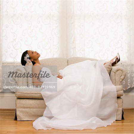 African-American bride lying on love seat.