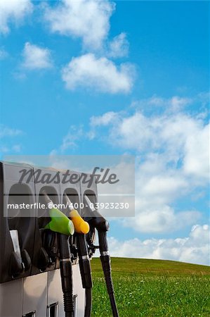 Three gas pump nozzles over a nature background