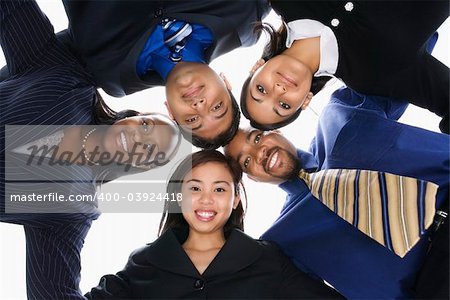 Low angle portrait  of multi-ethnic business group of men and women in huddle looking at viewer.