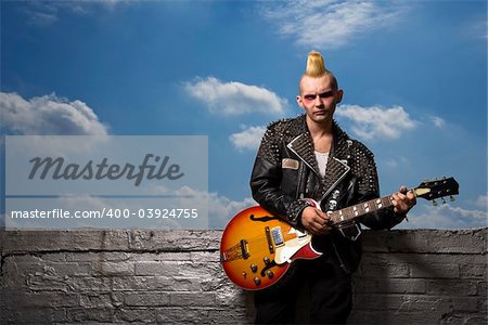 Portrait of mid-adult Caucasian male punk holding guitar.