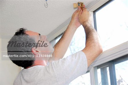 Man installing window blinds in a house