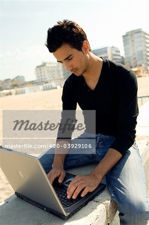 Young man using a personal computer while sitting outdoor