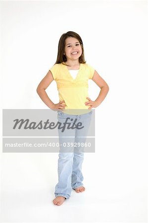 Five year old female child standing on white background smiling wearing casual clothes