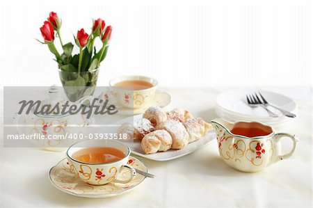 Two cups of tea with small sweet rolls