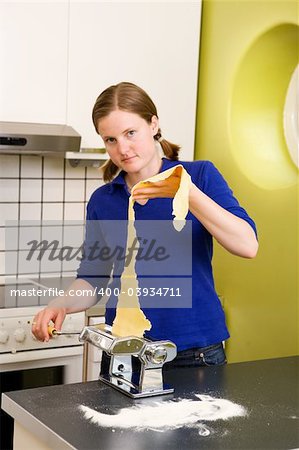 A young woman making pasta in an apartment kitchen.